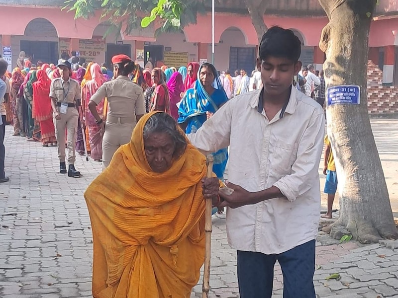 एक युवक बुजुर्ग महिला को सहारा देकर मतदान केंद्र तक ले गया