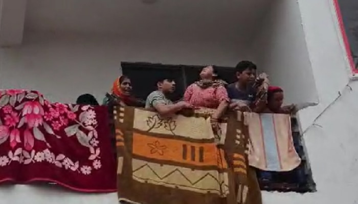 नाथूपुर में तोड़फोड़ अभियान से मकान को टूटने से बचाने के लिए बालकनी में लटकी महिला